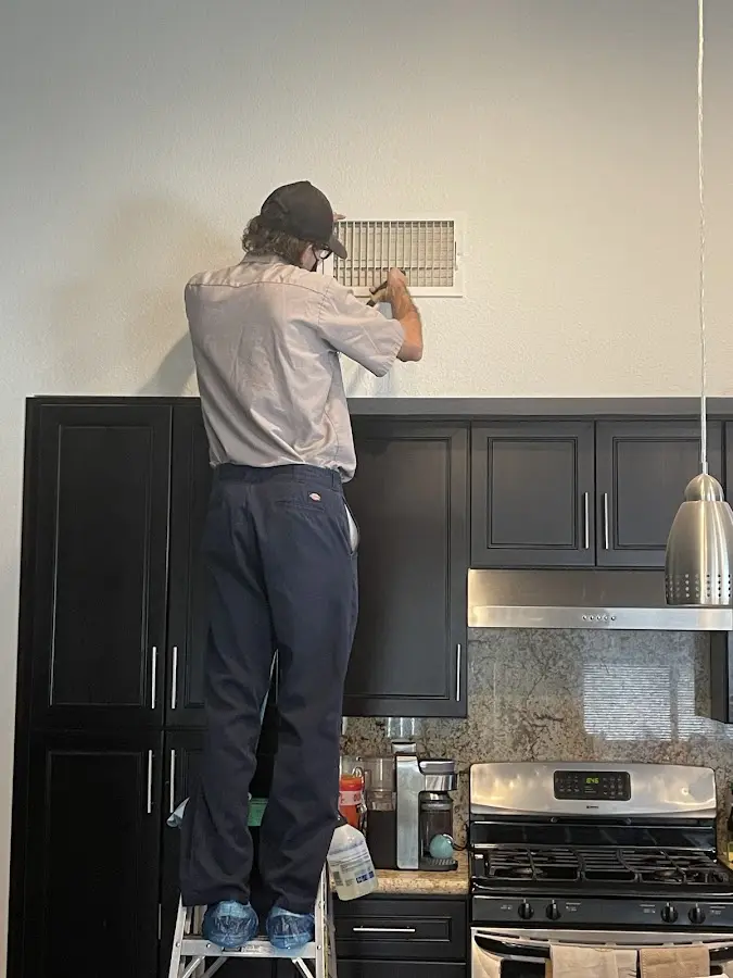 Technician inspecting an air vent during HVAC service in Marquette